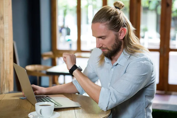 Joven comprobando el tiempo en la cafetería —  Fotos de Stock