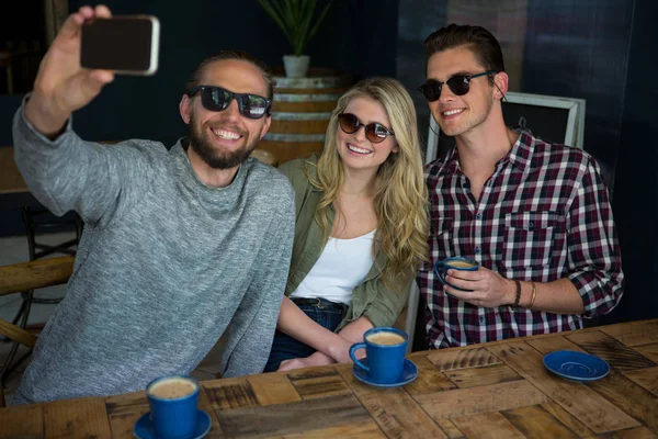 Мужчина с друзьями делает селфи в кафе — стоковое фото