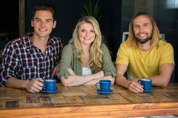 Amigos tomando café na mesa de madeira no café — Fotografia de Stock