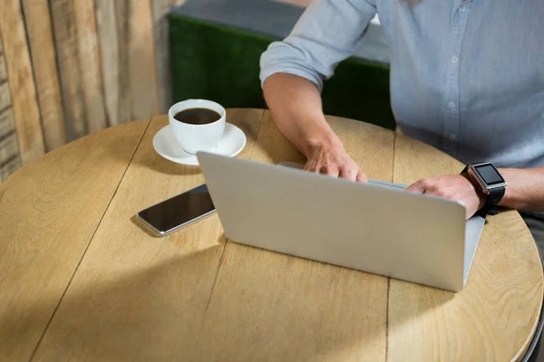 Чоловік використовує ноутбук за столом у кав'ярні — стокове фото
