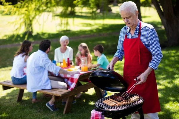 Homme barbecue avec la famille en arrière-plan — Photo