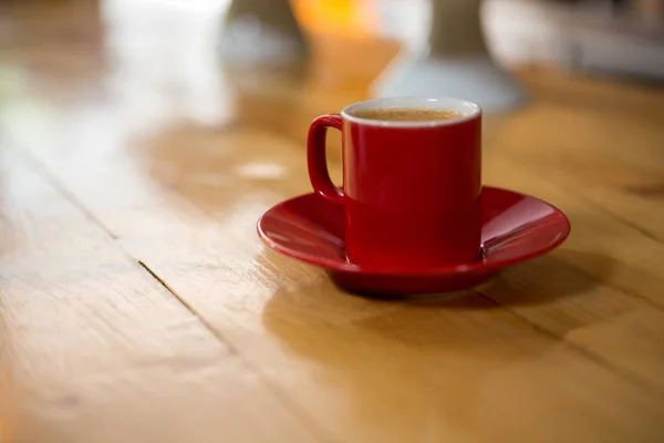 Красная чашка и блюдце на столе — стоковое фото