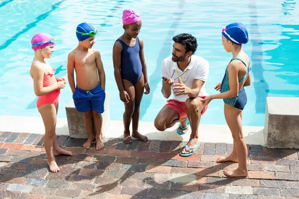 Instructor entrenando a los niños junto a la piscina — Foto de Stock