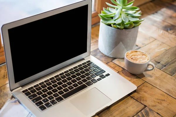 Laptop por xícara de café na cafetaria — Fotografia de Stock