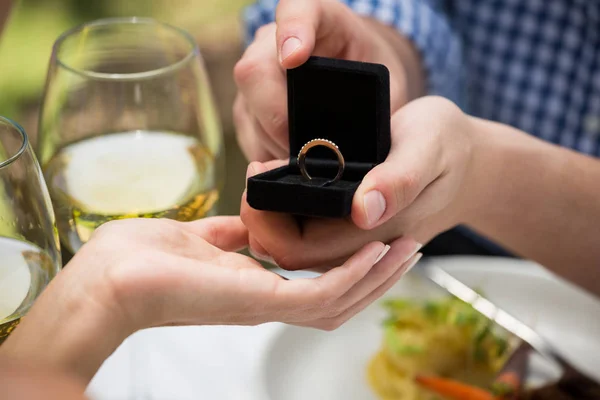 Homem dando anel de noivado para mulher no restaurante ao ar livre — Fotografia de Stock