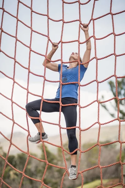 Fit vrouw klimmen een net tijdens hindernissenparcours — Stockfoto