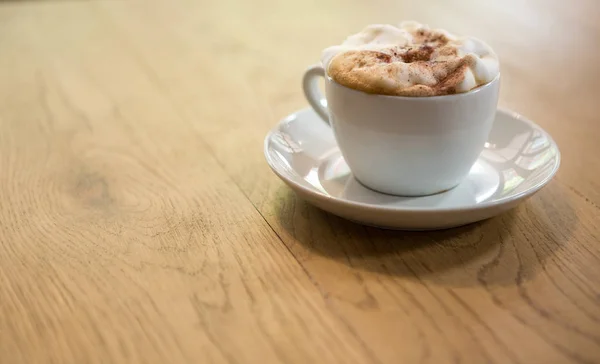 Kávéscsésze a krémes bevezetésekor a kávézó asztal — Stock Fotó