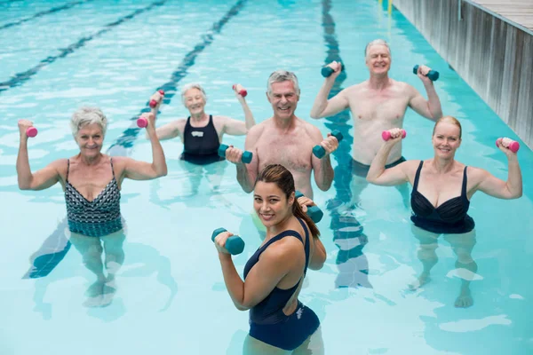 Senior swimmers and trainer lifting dumbbells — Stock Photo, Image