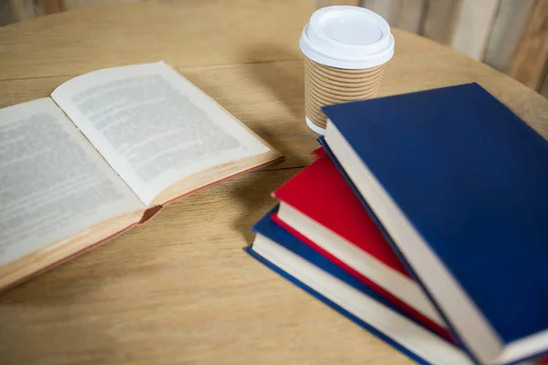 Libros y taza de café desechable en la mesa —  Fotos de Stock