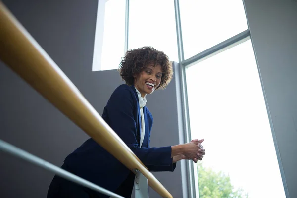 Businesswoman leaning over the railing of staircase — Stock Photo, Image