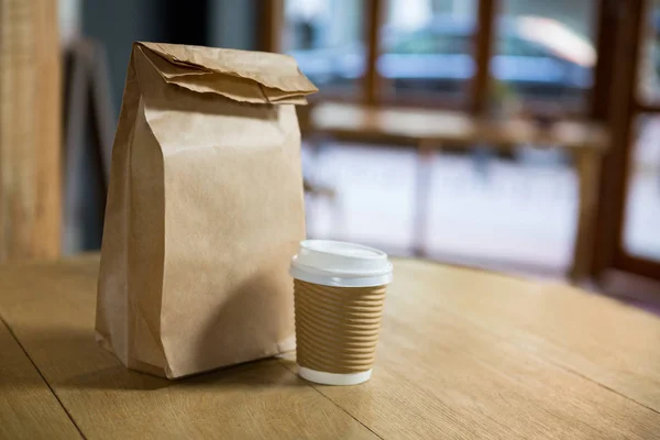 Copo de café descartável e saco na mesa — Fotografia de Stock