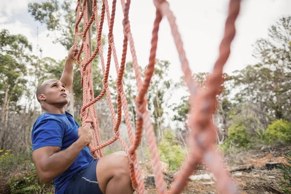 Fit man grimper un filet pendant la course d'obstacles — Photo