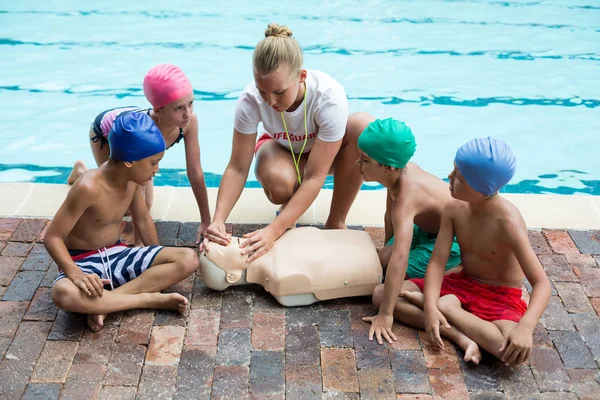Bagnino che dà addestramento di salvataggio ai bambini a bordo piscina — Foto Stock