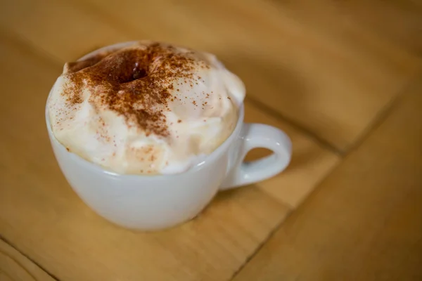 Cangkir kopi dengan buih krim di atas meja — Stok Foto