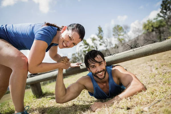 Smiling fit woman helping man crawling — Stock Photo, Image