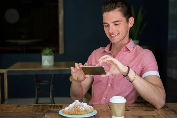 Homem fotografando comida na mesa no café — Fotografia de Stock