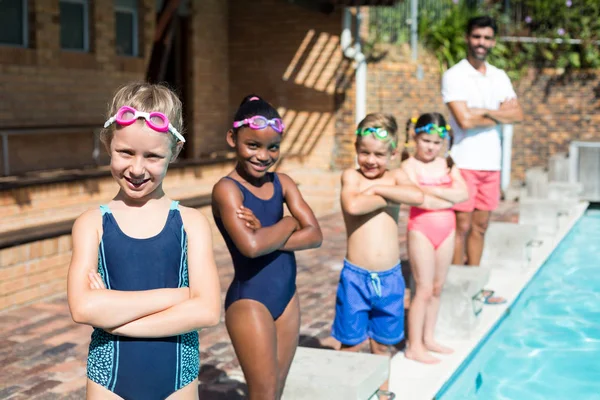 Pequenos nadadores confiantes com instrutor masculino à beira da piscina — Fotografia de Stock