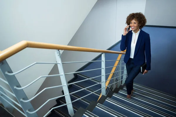 Podnikatelka, mluvit na mobilním telefonu při lezení kroky — Stock fotografie