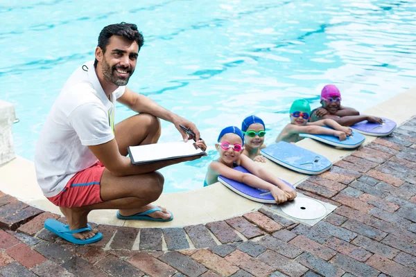Ausbilder mit kleinen Schwimmern am Beckenrand — Stockfoto