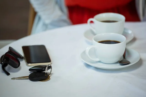 Кофейные чашки и личные принадлежности на столике кафе — стоковое фото