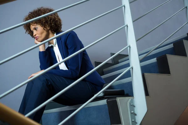 Orolig affärskvinna som sitter på stegen — Stockfoto