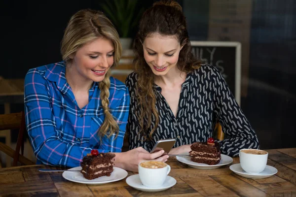 Unga kvinnor som använder smart telefon i café — Stockfoto
