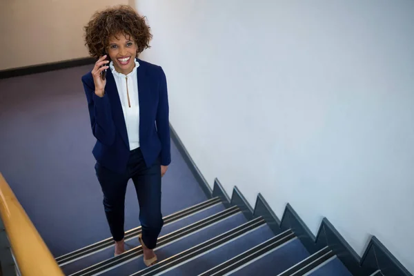 Mujer de negocios hablando por teléfono móvil mientras camina arriba —  Fotos de Stock