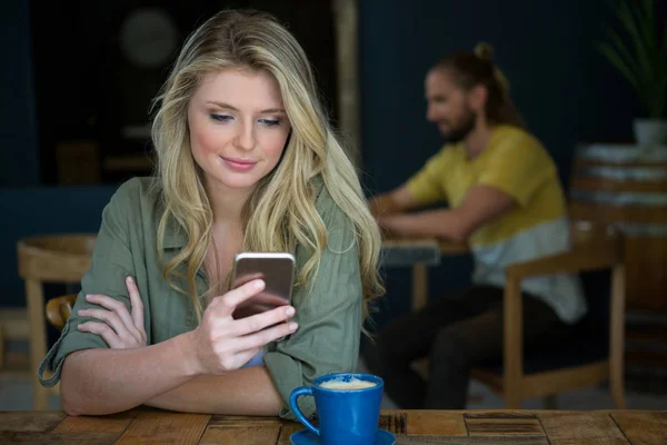 Жінка використовує мобільний телефон за столом — стокове фото
