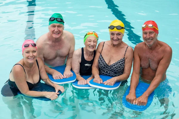 Seniores nadadores posando com kickboards na piscina — Fotografia de Stock