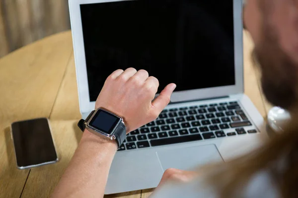 Hombre usando reloj inteligente con ordenador portátil y teléfono —  Fotos de Stock