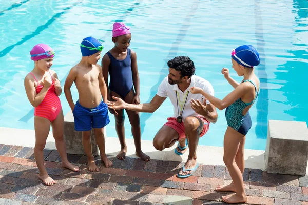 Тренер-мужчина помогает детям у бассейна — стоковое фото
