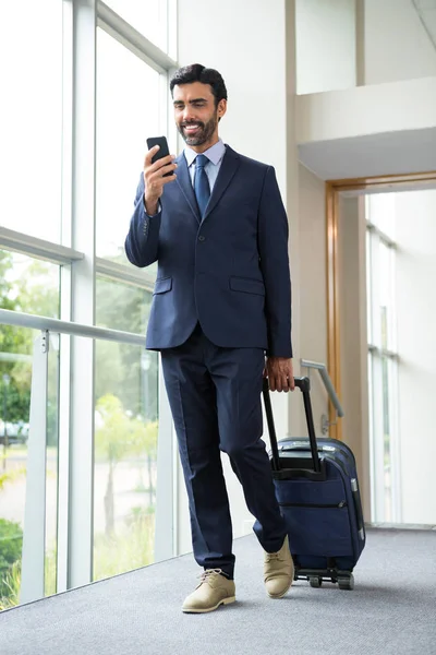 Empresario con bolsa de carro usando teléfono móvil — Foto de Stock