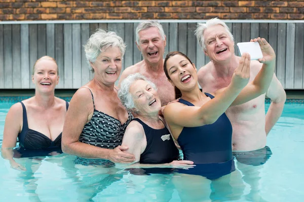 Female trainer taking selfie with senior swimmers — Stock Photo, Image