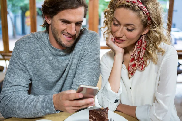 Par med smart telefon vid bord i café — Stockfoto
