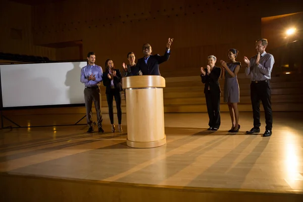 Керівник бізнесу виступає з промовою, а колеги аплодують — стокове фото