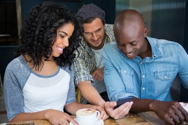 Друзья, пользующиеся мобильным телефоном в кафе — стоковое фото