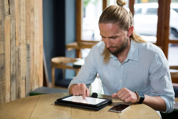 Человек с цифровой табличкой за деревянным столом — стоковое фото
