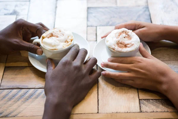 Multi étnica pareja manos sosteniendo tazas de café — Foto de Stock