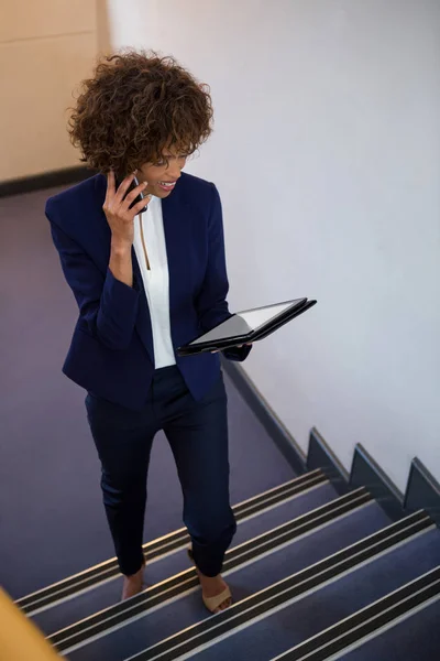 Mujer de negocios hablando en el teléfono móvil mientras usa la tableta digital — Foto de Stock