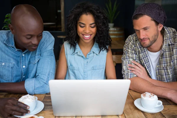 Smiling friends using laptop at table — Stock Photo, Image