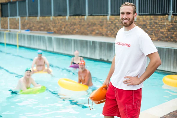 Salvavidas macho de pie mientras nadadores nadan en la piscina — Foto de Stock