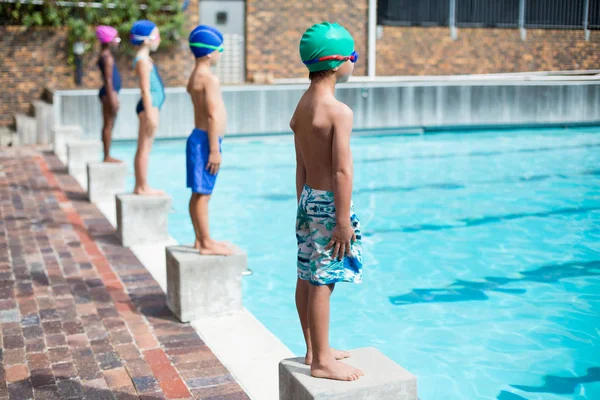 Nadadores de pé em blocos iniciais na beira da piscina — Fotografia de Stock