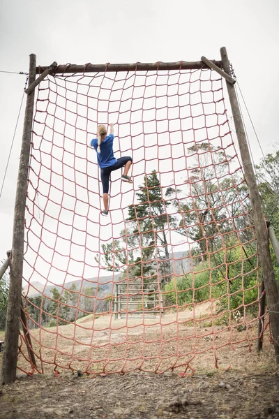 Woman climbing a net during obstacle course — Stock Photo, Image