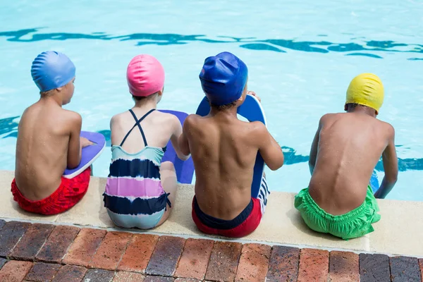 Mädchen und Jungen sitzen am Pool — Stockfoto