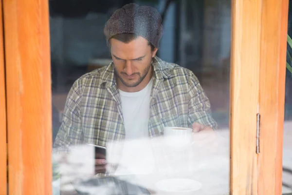 Člověk používající mobilní telefon v kavárně vidět oknem — Stock fotografie
