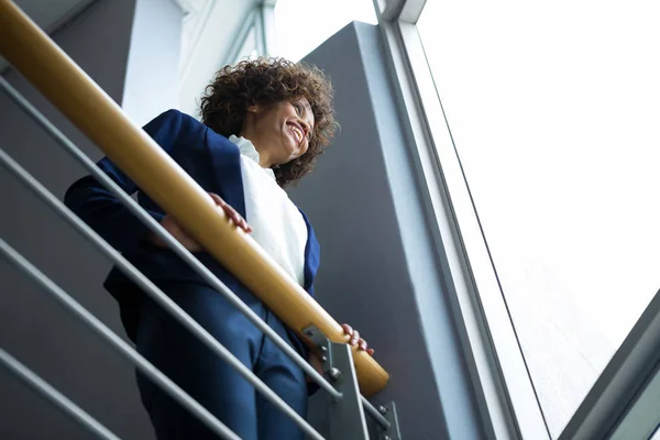 Businesswoman leaning over the railing of staircase — Stock Photo, Image