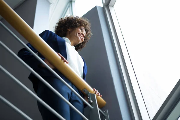 Geschäftsfrau lehnt sich über Treppengeländer — Stockfoto