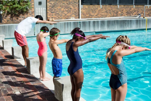 Instrutor e pequenos nadadores se preparando para saltar na piscina — Fotografia de Stock