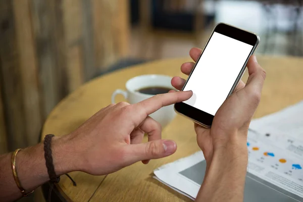 Man using mobile phone at table in cafeteria — Stock Photo, Image