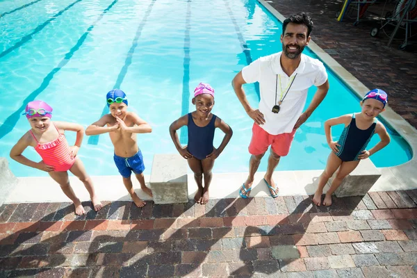 Istruttore maschio con bambini a bordo piscina — Foto Stock